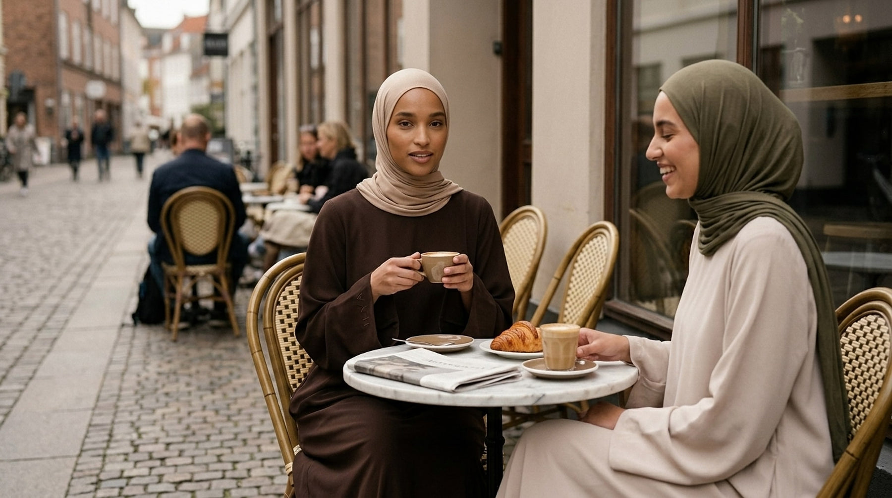 To kvinder i ILYA abayas på en caféterrasse