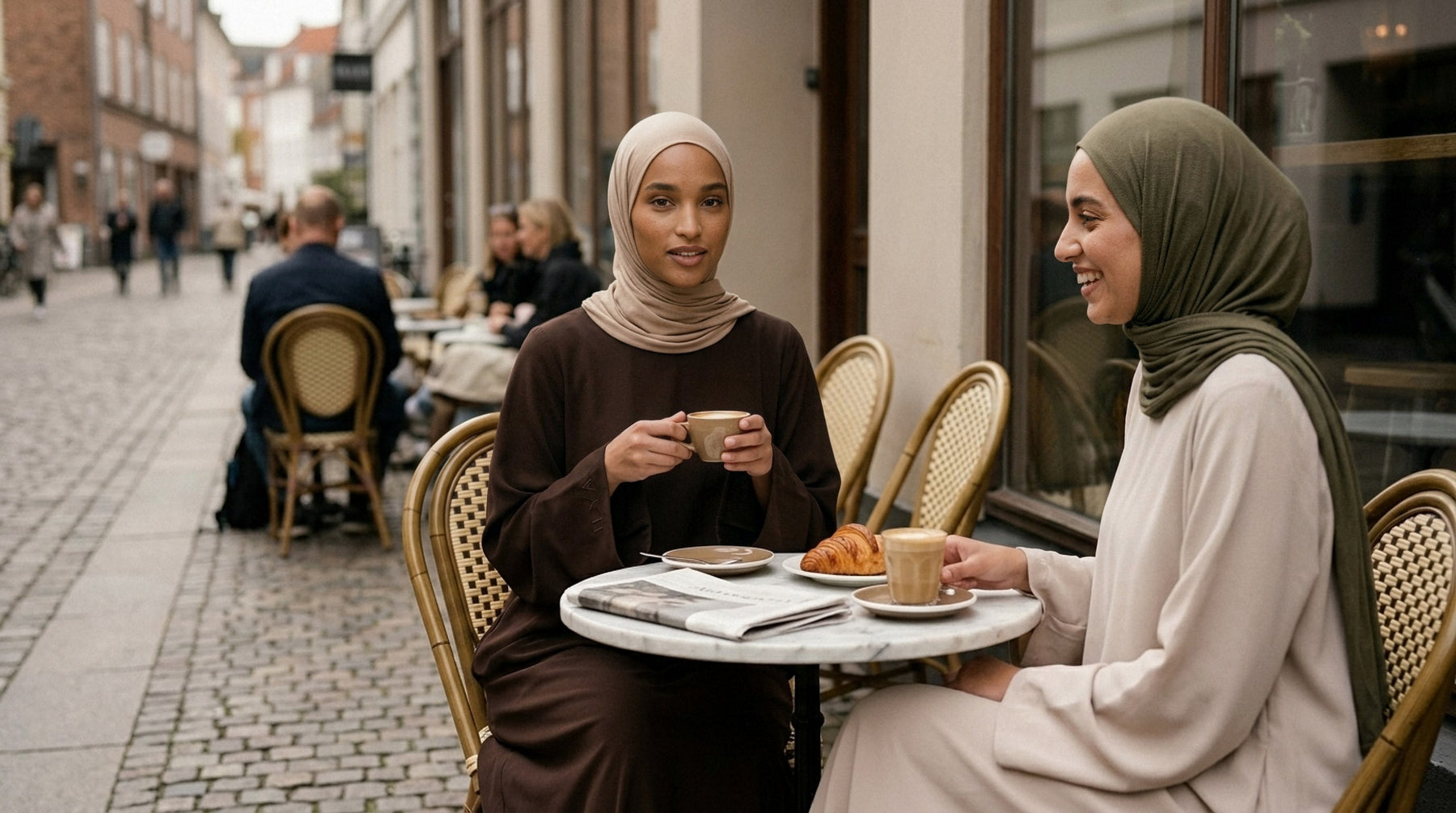 To kvinder i ILYA abayas på en caféterrasse